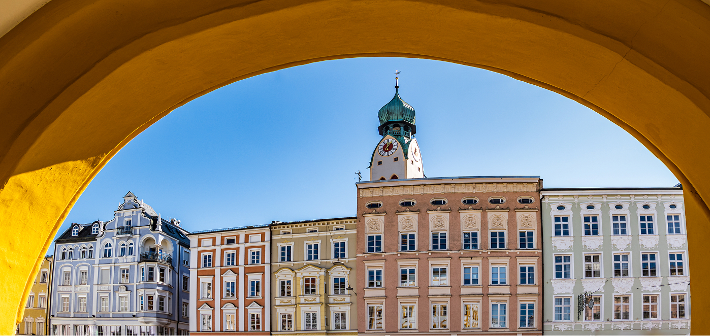 Historisches Gebäude in Rosenheim mit Kirchturm im Hintergrund